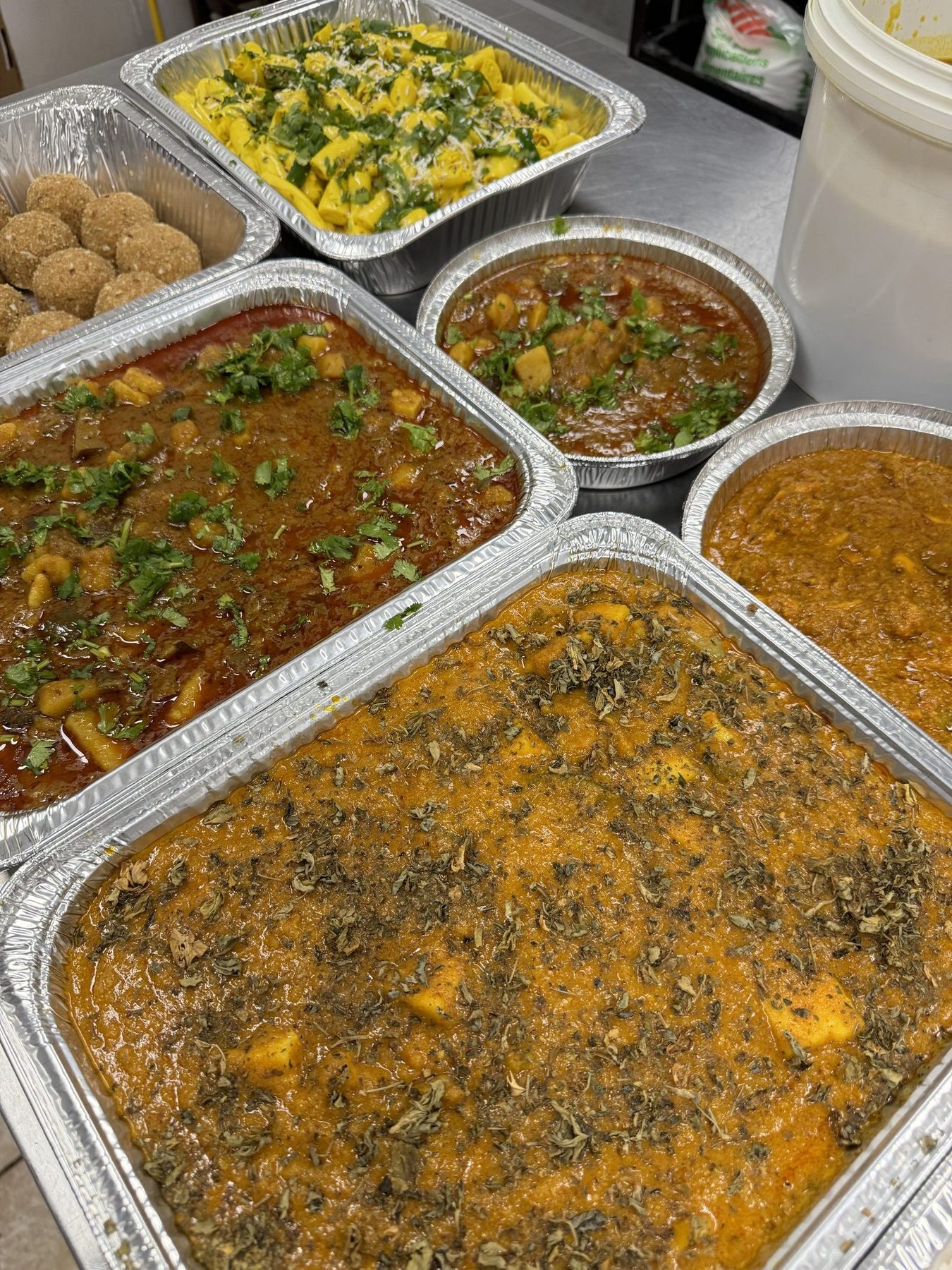 Large catering trays of curries and rice for a family plan