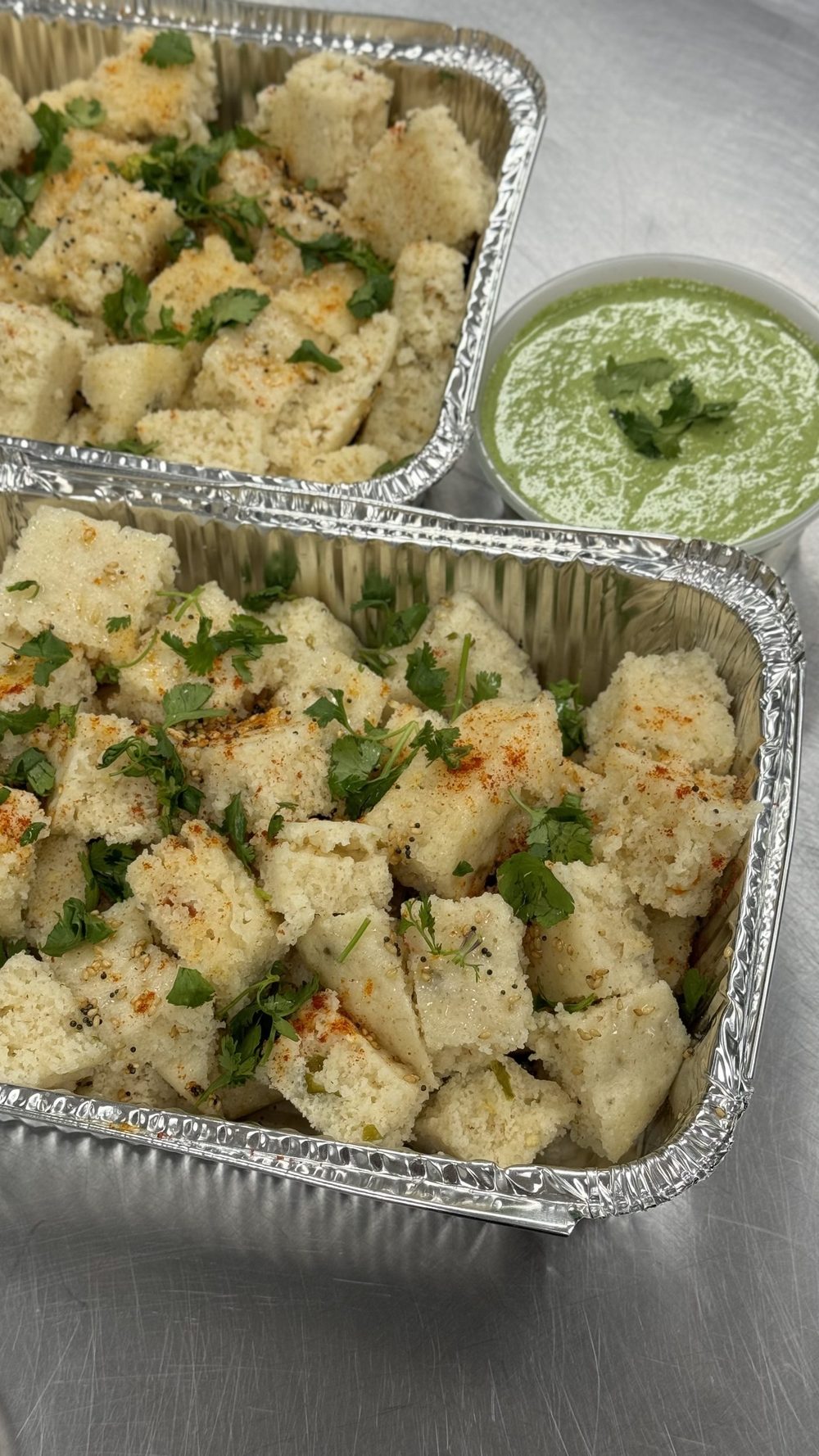 Trays of soft khaman, tempered and served with green chutney