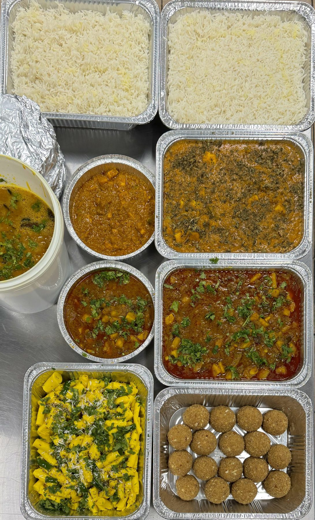Trays of sabji, rice, khandvi and laddu