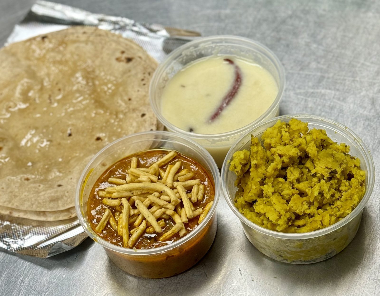 Packed tiffin containers of roti, kadhi, sev and sabji